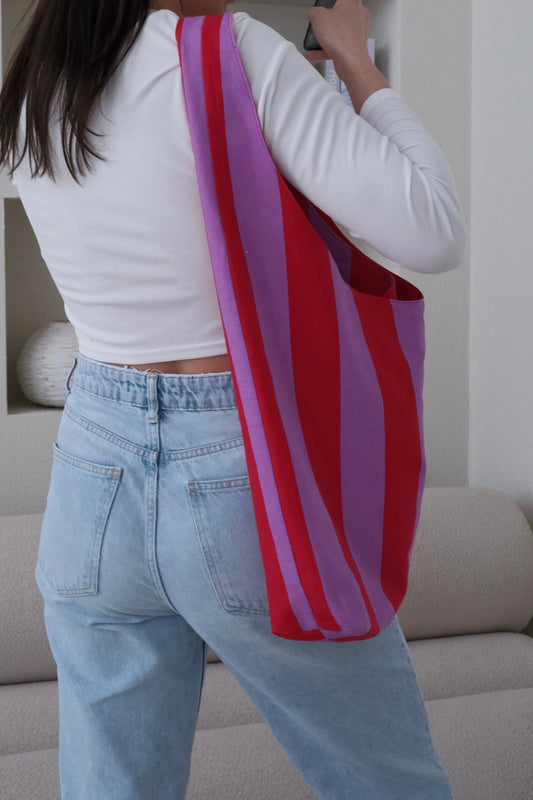 Person holding a red and pink striped bag in a living room setting