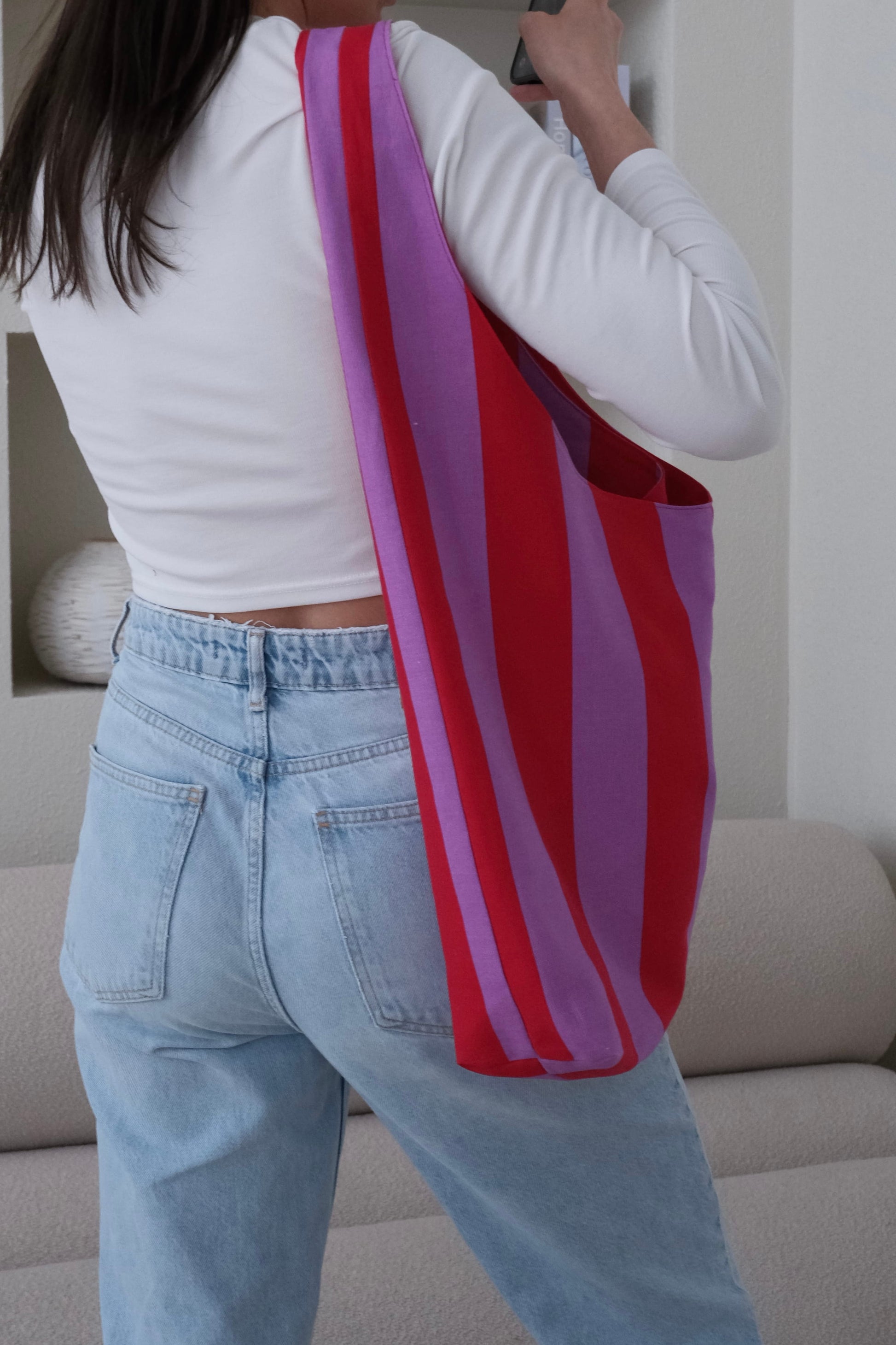Person holding a red and pink striped bag in a living room setting