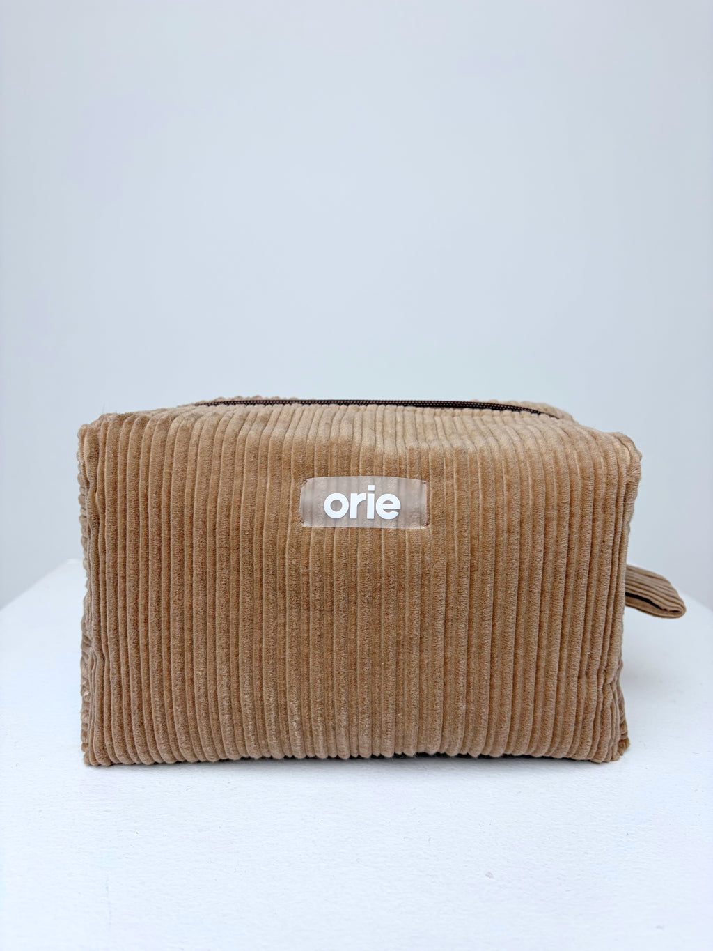 Brown makeuo bag pouch with 'orie' label on a white background
