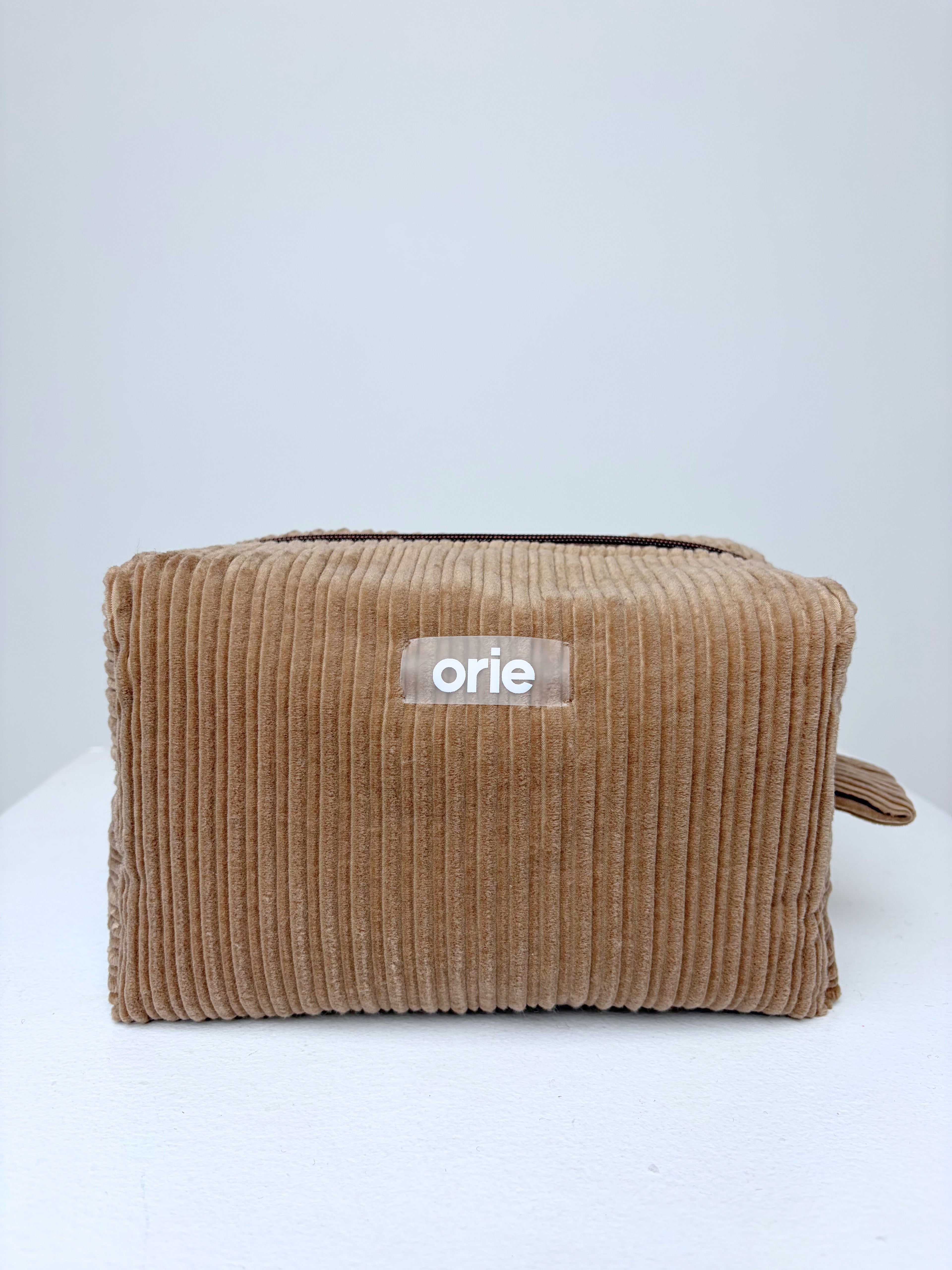 Brown makeuo bag pouch with 'orie' label on a white background