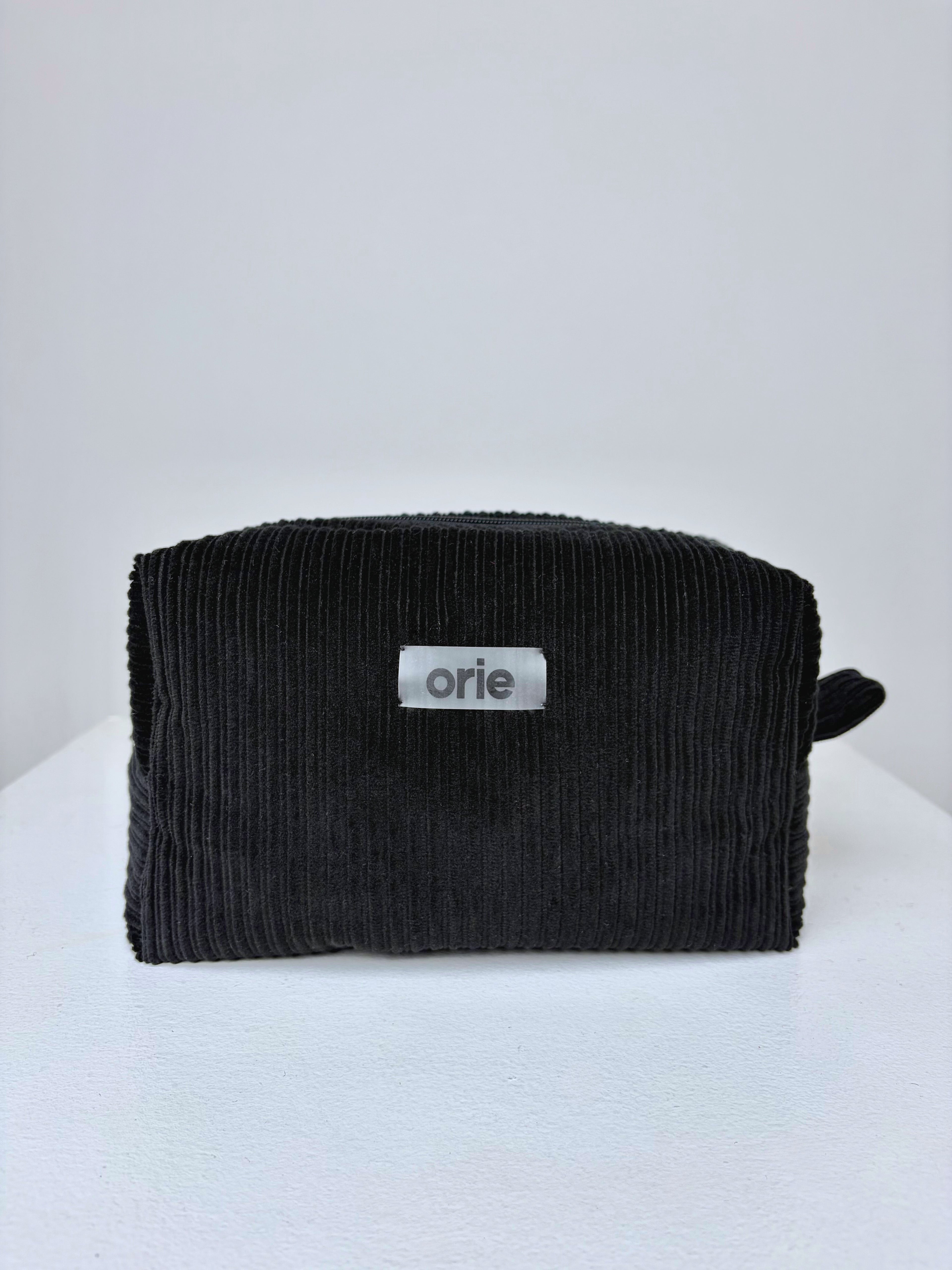 Black textured makeuo bag with 'orie' logo on a white background