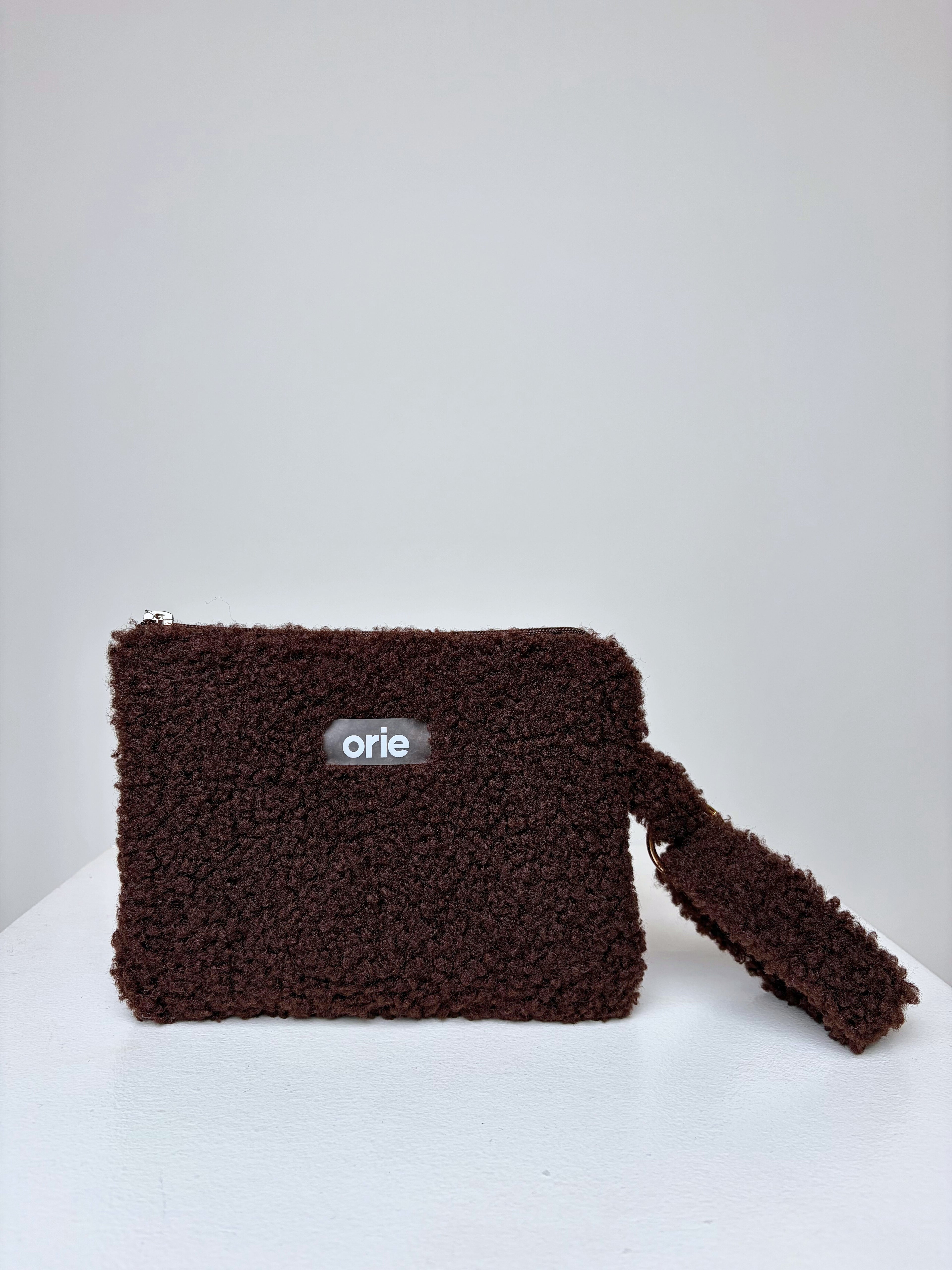 Brown teddy pouch with 'orie' logo on a white background