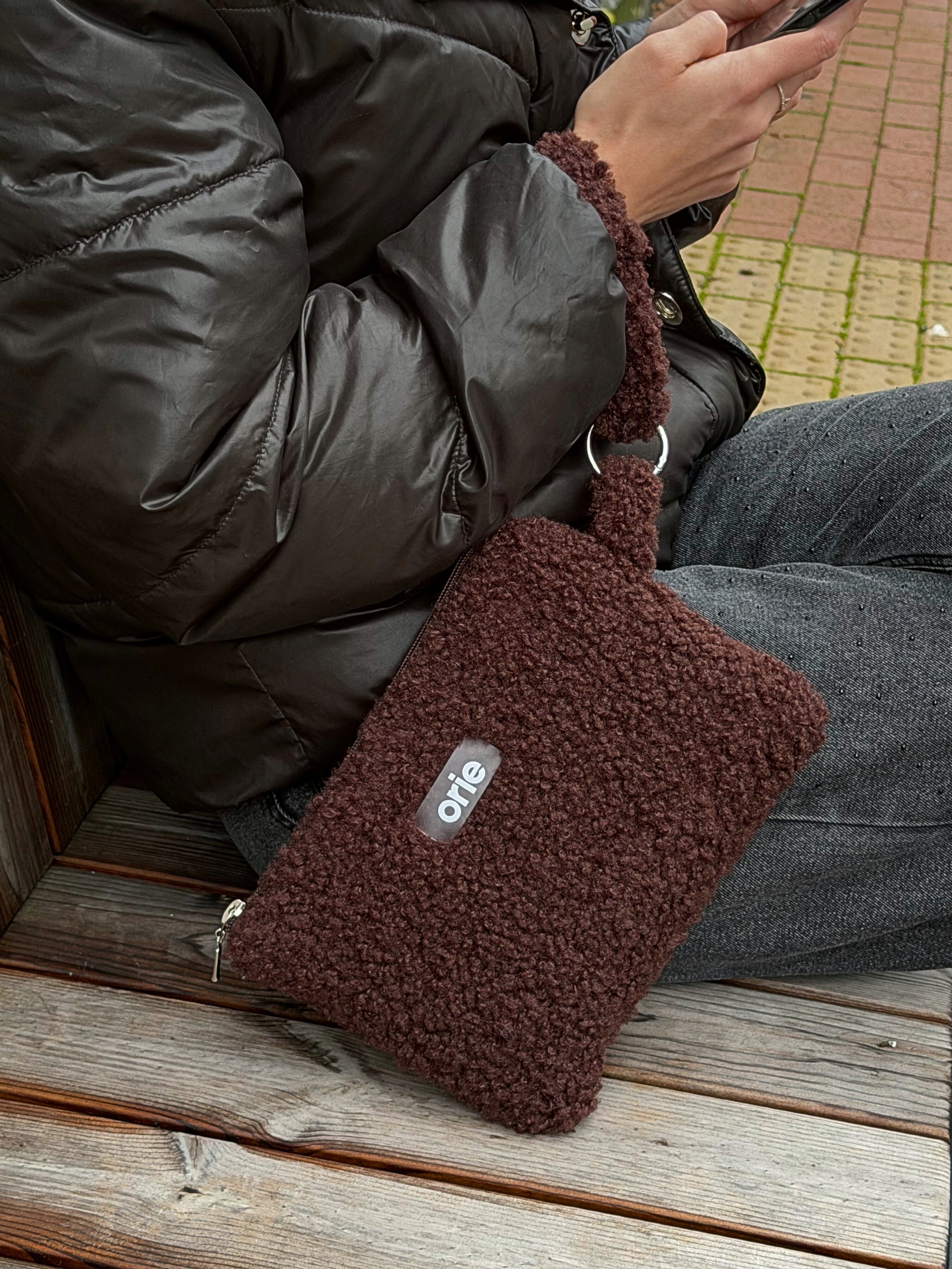 Brown textured teddy pouch with a brand logo on a wooden surface