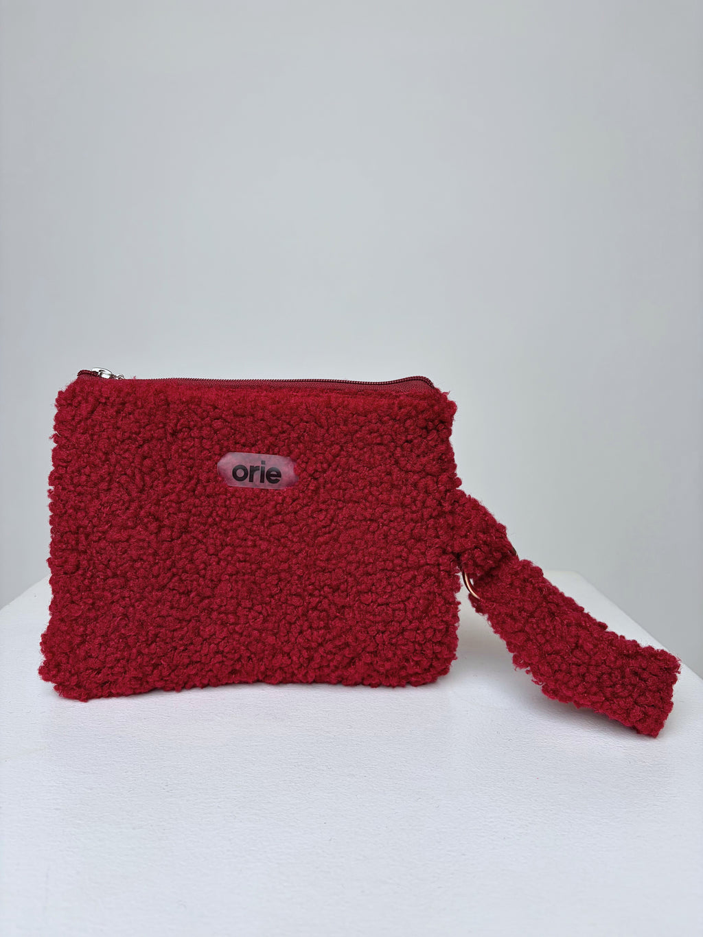 Red teddy pouch with a visible brand logo on a white background