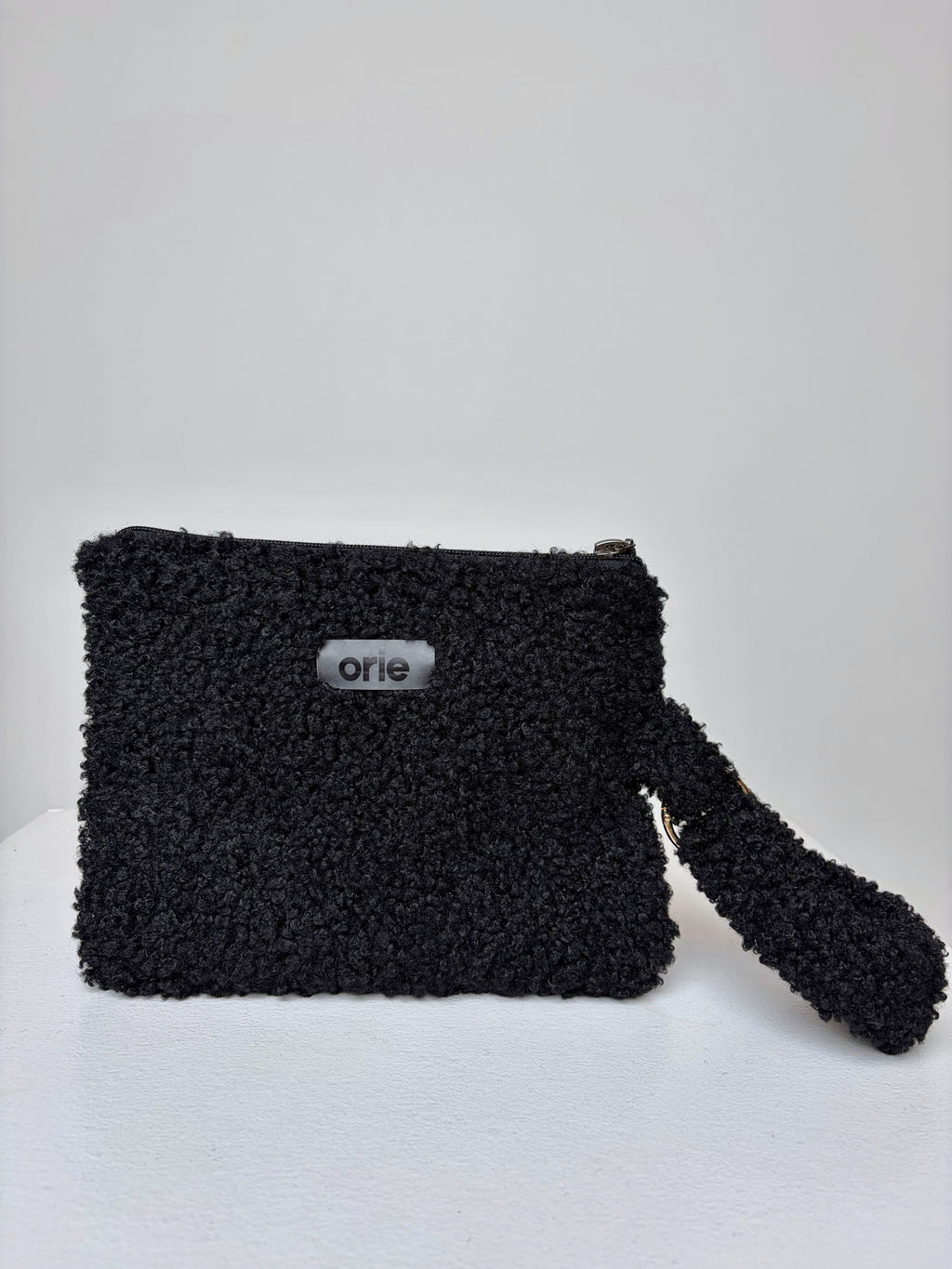 Black teddy pouch with 'orie' branding on a white background